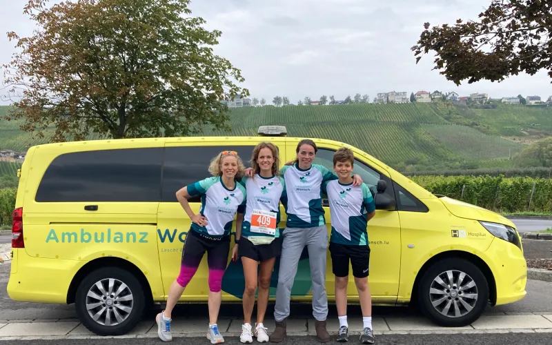 four ladies in front of a yellow ambulance dressed in ambulanzwonsch sports clothing taking part in the route du vin 2022